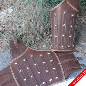 Puede incluir: Armadura de cuero marrón con tachuelas metálicas, que consta de una pieza de pecho y dos protectores de brazos. La armadura está diseñada para la recreación histórica o el cosplay.