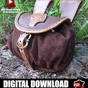 Puede incluir: Una bolsa de cuero marrón con cuerpo de ante y solapa decorativa de cuero. La bolsa tiene un cierre de hebilla y dos trabillas para cinturón. El texto "DESCARGA DIGITAL" está en la parte inferior de la imagen.