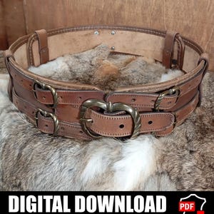 Può includere: Una cintura in pelle marrone con più cinturini e fibbie in ottone antico. La cintura presenta una grande fibbia a forma di cuore al centro ed è progettata con una costruzione a strati. L'immagine include il testo "DOWNLOAD DIGITALE" e "MODELLO E ISTRUZIONI INCLUSE."