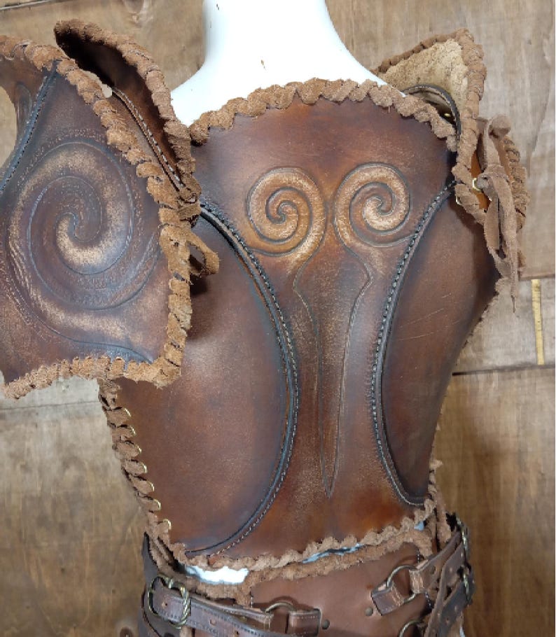 May include: A brown leather chest piece and shoulder armor set featuring embossed spiral patterns, decorative whip-stitched edges, and a waist belt with metal buckles. The armor displays a weathered finish with dark brown accents and visible lacing.