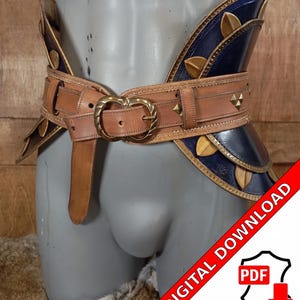 May include: A brown leather belt with a brass buckle and decorative metal accents. The belt is worn over a blue leather and metal hip piece with decorative metal accents.