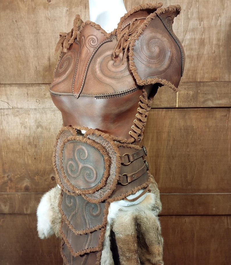 May include: A brown leather chest piece and belt set featuring embossed spiral and triskelion patterns. The armor includes shoulder guards, side lacing with leather cords, metal rings on the belt, and decorative frayed edges with faux fur accents.
