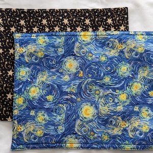 May include: Two placemats, one with a black background and gold stars and swirls, and the other with a blue background and a swirling yellow and white pattern reminiscent of Van Gogh's Starry Night.