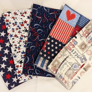 May include: Five fabric squares with patriotic designs. The squares feature red, white, and blue stars, stripes, confetti, and a heart. One square has the text "1776" and "John Adams" printed on it.