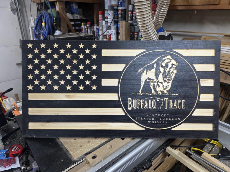 May include: Wooden American flag with a black finish and natural wood stripes. The right side features a circular emblem with a bison and the words "Buffalo Trace Kentucky Straight Bourbon Whiskey."