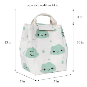May include: White canvas lunch bag with a green cloud pattern and smiling faces. The bag has a top handle and measures 13 inches tall, 10 inches wide, and 7 inches deep. The bag expands to 14 inches wide.