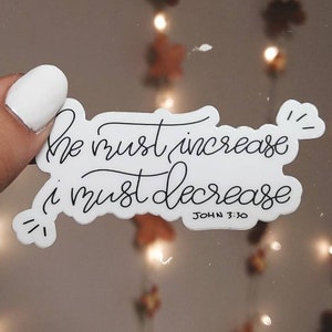 May include: White sticker with black calligraphy that reads "He must increase, I must decrease" with the scripture reference "John 3:30" below.