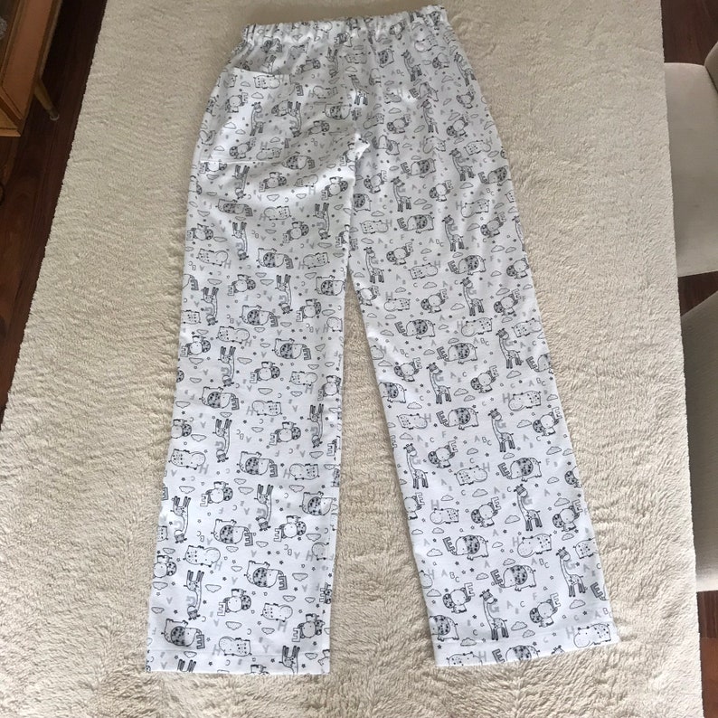 Puede incluir: Pantal&oacute;n de pijama blanco con estampado en blanco y negro de animales y letras.