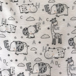 Puede incluir: Tela blanca con un patr&oacute;n repetido de ilustraciones de animales en blanco y negro. Los animales incluyen elefantes, hipop&oacute;tamos, jirafas y nubes. Las letras A, B, C, E, G y H est&aacute;n dispersas por todo el patr&oacute;n.