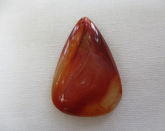 May include: A teardrop-shaped carnelian gemstone pendant with red, orange, and white banding. The pendant is polished and has a smooth, glossy finish.