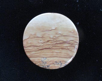 May include: A round, light brown stone coaster with a layered pattern of brown and white. The stone has a natural, organic look.