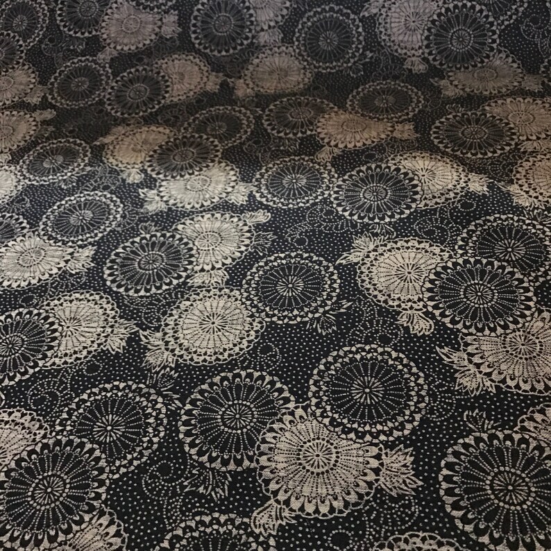 May include: Black fabric with a white floral pattern. The pattern features repeating circles with a radial design.