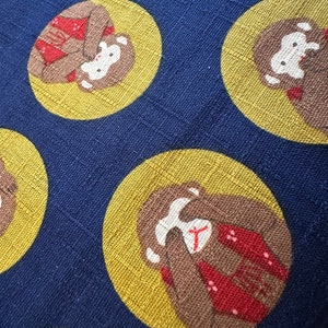 May include: A blue fabric with a repeating pattern of brown monkeys wearing red and white outfits. The monkeys are in yellow circles on a dark blue background.