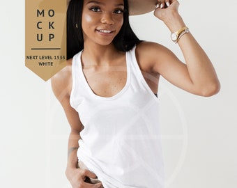Pode incluir: Uma mulher vestindo um top branco sem mangas e shorts cáqui, segurando um chapéu fedora marrom. O texto "MOCK UP NEXT LEVEL 1533 WHITE" é visível na imagem.