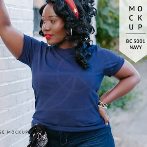 May include: A woman wearing a navy blue t-shirt with a red headband. The t-shirt is a blank canvas for customization.  The text "MOCK UP BC 3001 NAVY" is visible in the image.