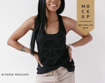 Pode incluir: Uma mulher vestindo um top preto sem mangas com o texto "MOCK UP" e "NEXT LEVEL 1533 BLACK" em uma etiqueta dourada. Ela está vestindo calças bege e tem as mãos nos quadris.