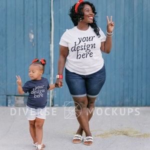 Puede incluir: Una mujer y un niño con camisetas a juego. La mujer lleva una camiseta blanca con el texto "your design here" impreso. El niño lleva una camiseta azul marino con el texto "your design here" impreso. Están de pie frente a una pared de madera azul.