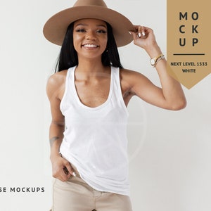 Pode incluir: Uma mulher vestindo um top branco sem mangas e um chap&eacute;u fedora marrom. O top &eacute; uma tela em branco para personaliza&ccedil;&atilde;o. A imagem &eacute; rotulada como "MOCK UP" com o texto "NEXT LEVEL 1533 WHITE".