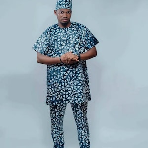 May include: A man wearing a blue and white patterned outfit with a matching hat. The outfit includes a long-sleeved shirt and trousers.