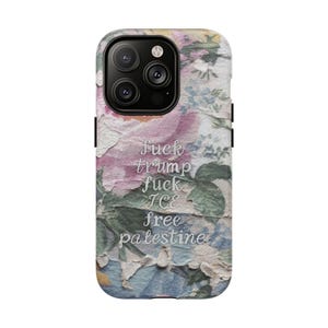 May include: A phone case with a floral design in pink, blue, and yellow hues. The case features the text "fuck trump fuck ICE free palestine" in a white, stylized font. The case has a black camera module.