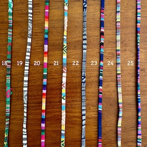 May include: A close-up of 8 colorful woven cords with different patterns. The cords are numbered 18 through 25.