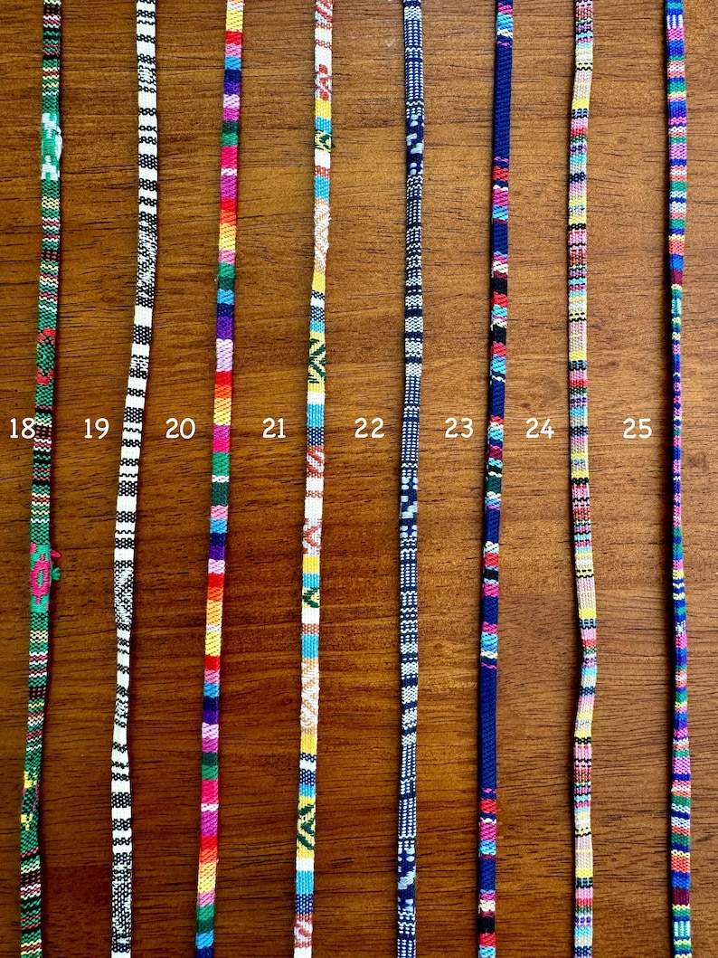 May include: A close-up of 8 colorful woven cords with different patterns. The cords are numbered 18 through 25.