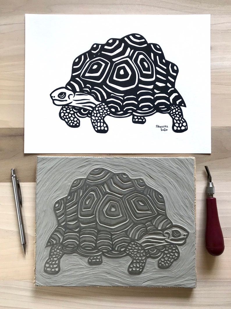 May include: A black and white linocut print of a tortoise with a detailed shell pattern. The print is on a white background and is signed and dated "S. Sanchez 2020".