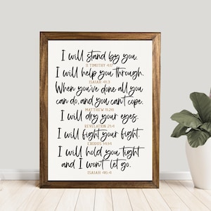 May include: A framed print with a white background and black script. The text includes inspirational quotes from the Bible. The frame is a dark brown color. The print is displayed on a white wall.