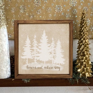 May include: A framed print with a beige background and white silhouettes of pine trees. The text "heaven and nature sing" is printed below the trees.
