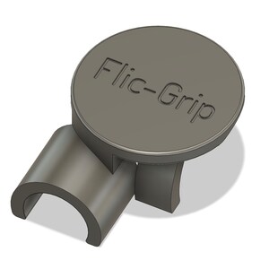 Puede incluir: Un dispositivo de plástico gris con el texto "Flic-Grip" en la parte superior circular. El dispositivo tiene una base curva y dos patas de soporte. El diseño parece ser una representación 3D.