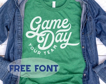 May include: Green t-shirt with white text that reads "Game Day Your Team" and the words "FREE FONT" in blue text below. The shirt is folded and laid on a blue denim shirt. The text "SVG | DXG | PNG | EPS" is at the bottom of the image.