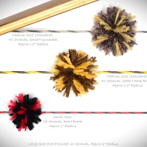 Può includere: Tre pompon di lana di diverse dimensioni per silenziatori di corda per arco. I pompon sono realizzati con diversi colori di lana, tra cui rosso, nero, marrone, giallo e sabbia. Il testo sull'immagine recita: "Dimensione media (standard) 40 fili, sabbia + metallo. Raggio di circa 1,5 pollici", "Dimensione piccola 28 fili, rosso + nero. Raggio di circa 1 pollice", e "Dimensione media (standard) 40 fili, cedro + marrone scuro. Raggio di circa 1,5 pollici".