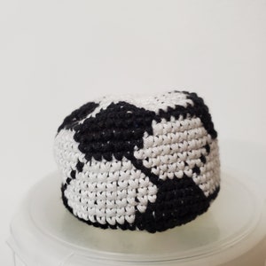 May include: A black and white crocheted ball with a textured surface.