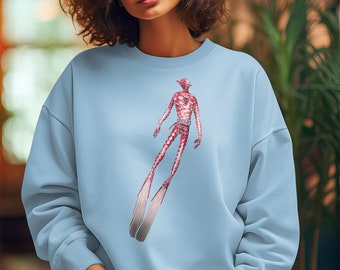 Könnte beinhalten: Ein hellblauer Pullover mit einem Grafikdruck eines roten und weißen Wesens mit Flossen. Das Wesen trägt einen Gürtel und hat ein rotes und weißes Muster.