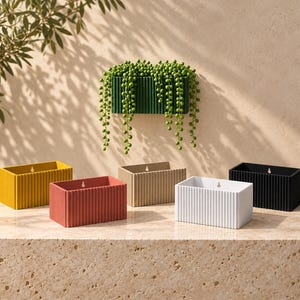 May include: A collection of rectangular wall-mounted planters featuring a vertical ribbed texture. The set includes individual units in mustard yellow, terracotta red, beige, white, and black, each with a small keyhole slot for mounting.