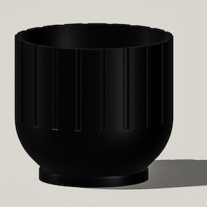 May include: A black, cylindrical planter with vertical grooves. The planter has a rounded base and a slightly flared top. The design is modern and minimalist, suitable for indoor or outdoor use. The planter casts a shadow on the light-colored surface.