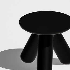 May include: A black, three-legged stool with a round seat. The stool is made of a smooth, glossy material.