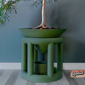 Peut inclure: Un pot en céramique vert avec un arbre à l'intérieur est posé sur un support vert avec un plus petit pot vert en dessous. Le support a un design géométrique avec quatre pieds.