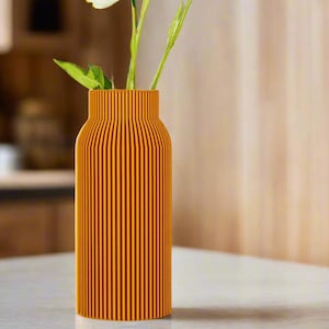 May include: A vase with a ribbed design in a bright orange color, holding a bouquet of white flowers.