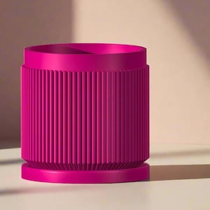 Peut inclure: Un récipient cylindrique magenta vif avec des détails côtelés verticaux. Le récipient a une base plate et un sommet légèrement plus large. Le fond est rose clair avec une ombre.