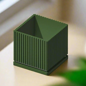 May include: A dark green square planter with vertical ridges. The planter has a square opening at the top.