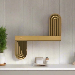 May include: A gold metal shelf unit with a curved design. The shelf is mounted on a white wall.