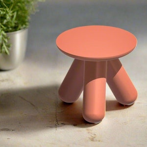 May include: A small, coral-coloured stool with four rounded legs. The stool is made of a smooth, plastic-like material.