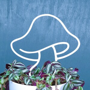 Peut inclure: Un support de plante en m&eacute;tal blanc en forme de champignon avec une plante verte et violette poussant dans un pot blanc.