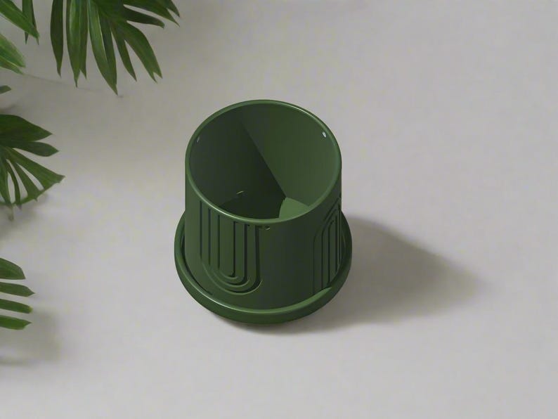 May include: A dark green ceramic planter with a geometric design. The planter has a wide base and a narrow opening.