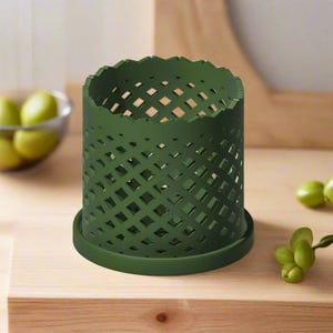 May include: A dark green, cylindrical, decorative planter with a diamond-shaped lattice pattern. The planter has a wide, flat base.