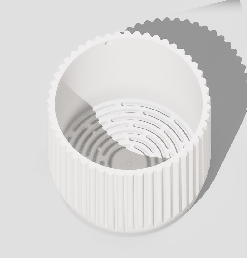 May include: White ceramic planter with a ribbed exterior and a drainage hole. The planter has a removable inner pot with a grid pattern.