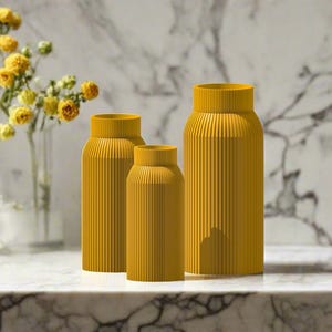 May include: Three yellow ceramic vases with a ribbed texture. The vases are arranged in a row from largest to smallest.