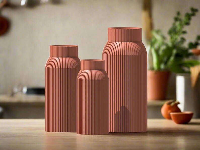 May include: Three terracotta-colored ceramic vases with a ribbed texture. The vases are arranged in a row from largest to smallest.