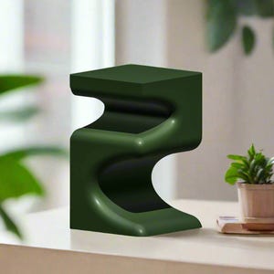 Pu&ograve; includere: Un tavolino laterale moderno verde scuro con un design curvo unico. Il tavolo ha un piano e una base quadrati, con una forma fluida e organica in mezzo. Il tavolo &egrave; alto circa 46 cm.
